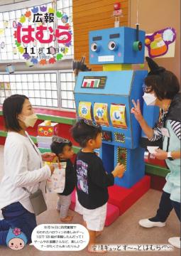 広報はむら11月1日号No.1080表紙　西児童館ハロウィンお楽しみデーで、ロボットのゲームで遊ぶ親子